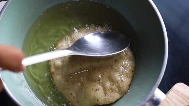 Indian bread or puri or pudi being fried in hot oil