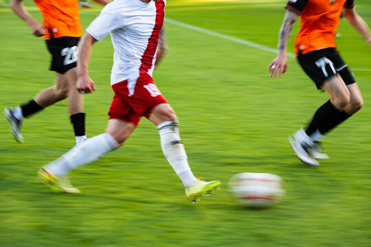 professional football player running with the ball on the green grass pitch during a match.