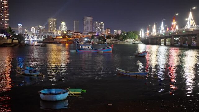 Nha Trang Vietnam. 01 06 2026 Nha Trang Vietnam. 01 06 2026 Night harbor view over Nha Trang waterfront with moored fishing boats, glowing bridge, city lights, blue coracle, wooden