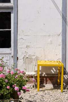 Vignette of bright yellow table against textured wall and flowers in Lisbon, Portugal