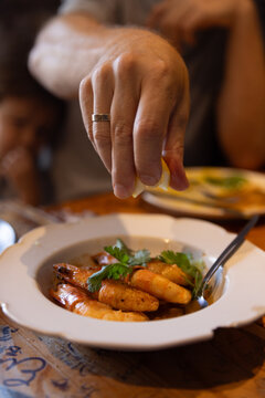 Male hand squeezing fresh lemon onto plate of shrimp in Portugal. 