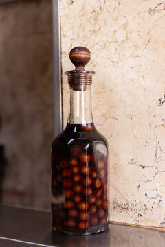 Clear bottle of infused and preserved cherries for ginja, ginjinha, traditional Portuguese cherry liqueur, next to a pour. 