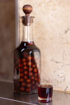 Clear bottle of infused and preserved cherries for ginja, ginjinha, traditional Portuguese cherry liqueur, next to a pour. 