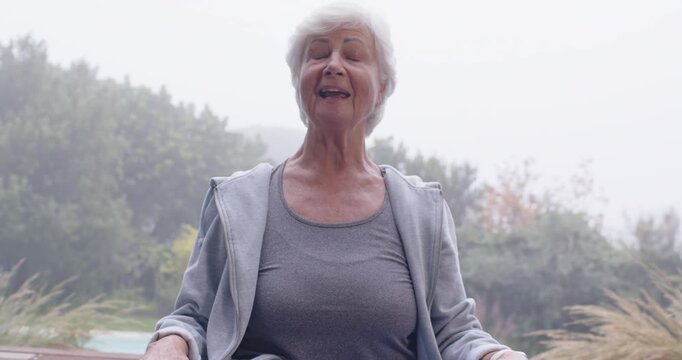Senior woman doing breathwork on bench outside turning head right smiling lifting chin in grey tank