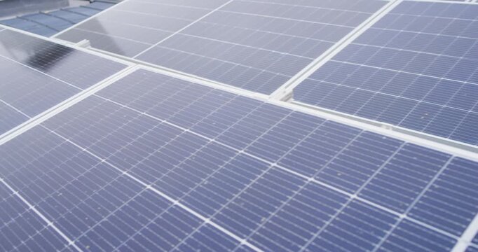 Camera is panning across bank of blue rooftop solar panels, revealing mounting rails for inspection