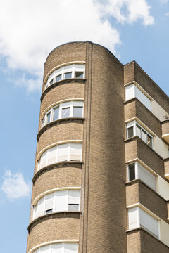 Brussels, Belgium. Curved Art Deco apartment building facade with rounded corner architecture under blue summer sky