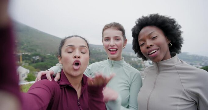 Diverse women friends wearing zip-up jackets at overlook, starting phone filming, singing, hugging