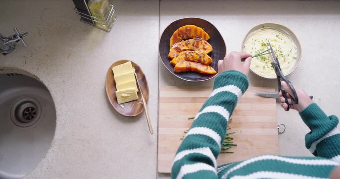 Diverse aproned women using scissors trimming chives into sauce bowl arranging carrots for serving