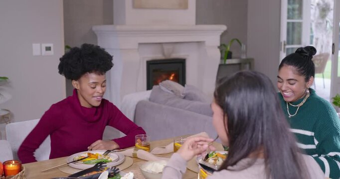 Diverse women friends laughing, eating at table as maroon sweater woman starting remark with forks