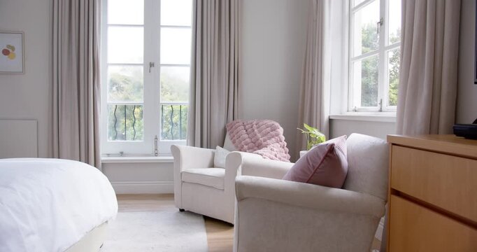 Camera is shifting right while cream armchairs are staying still in bedroom, centering dresser