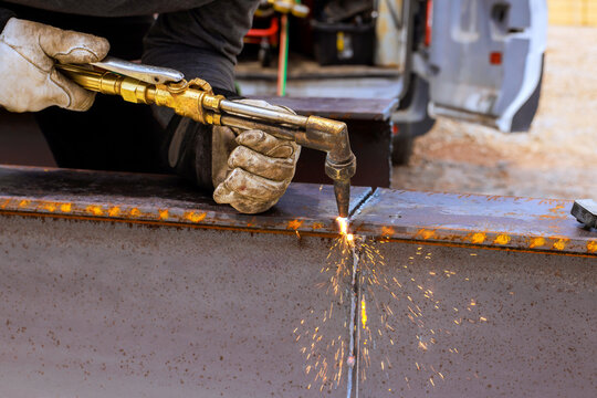Worker uses torch to cut metal in workshop tools lined up