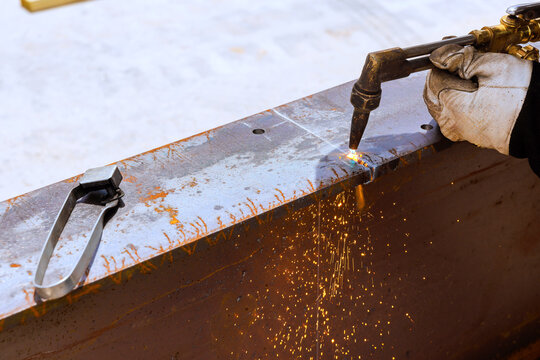 Worker uses torch to cut metal at construction site