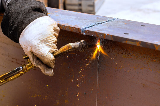 Worker uses torch to cut metal at construction site