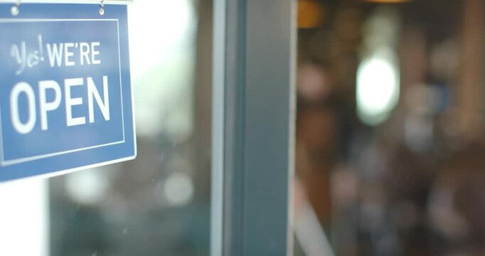 African American barber in apron seeing open sign and mopping shop floor with mop, preparing shop