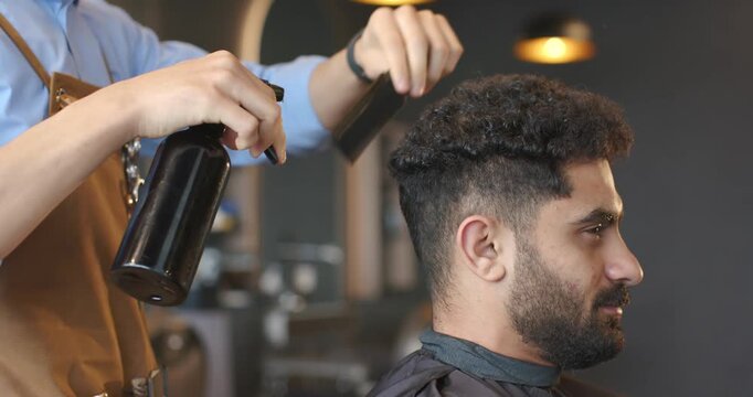 African American barber misting client's curls with spray bottle, combing shaping fade, copy space
