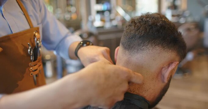 African American barber and client at shop, barber feeling nape then using clipper to finish fade