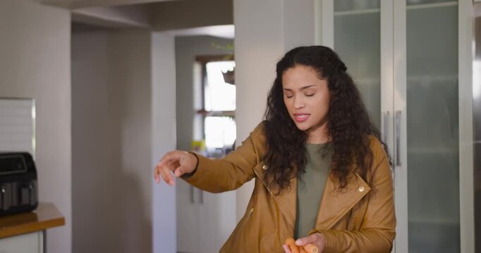 African American woman pointing offscreen, packing carrots into netbag at counter to store