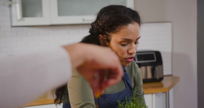 African American woman in apron squeezing lemon into cup with helper offering at counter to cook