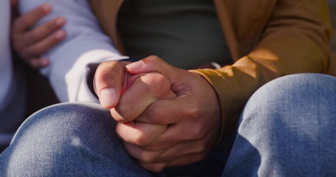 African American couple holding interlocked hands on denim knees, fingers uncurling for comfort
