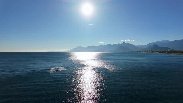 Scenic antalya cliff view overlooking sunlit mediterranean sea with distant taurus mountains.