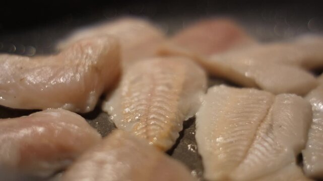 Close up Frying Fillet Hake Fish of Frying Pan With Oil. Roast Healthy Food. Fried Cod Fish Pieces Fillet With Spice Closeup. Healthy Diet Food Omega 3. Low-calorie white meat.