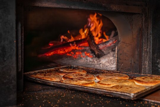 wood-fired oven bread, baked bread, rustic loaf, wood oven baking, traditional bread, golden crust, artisan bread, oven baked, firewood cooking, bread out of oven, brick oven, smoky flavor, crusty bre