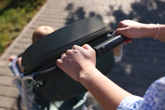 Baby carriage. Mother walking with her child in stroller outdoors, closeup