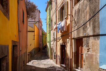 Fototapeta premium Narrow cobblestone street lined with colorful houses in the historic town of Bosa, Sardinia, Italy