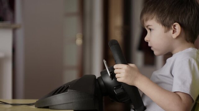 Boy Playing Racing Video Game in Game Console. Child Playing Computer Game in Headphones With Steering Wheel. Gamer With Headset Holding Steering Wheel Playing Video Game. Kid Gambling Addiction.