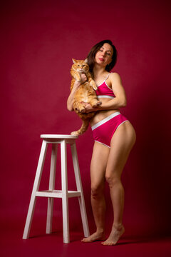 Woman in Pink Lingerie Holding Orange Cat