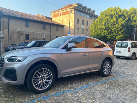Audi Q5 Sportback, modern luxury SUV, parked on a historic cobblestone street in Cremona, Lombardy, Italy