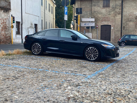 Modern KIA K5 sedan parked on an old cobblestone street in a historic European city center, combining new and old