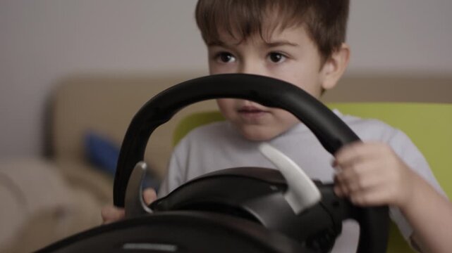 Boy Playing Racing Video Game in Game Console. Child Playing Computer Game in Headphones With Steering Wheel. Gamer With Headset Holding Steering Wheel Playing Video Game. Kid Gambling Addiction.