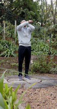 Vertical video: African American man starting lifting crossing hugging breathing in garden on pad