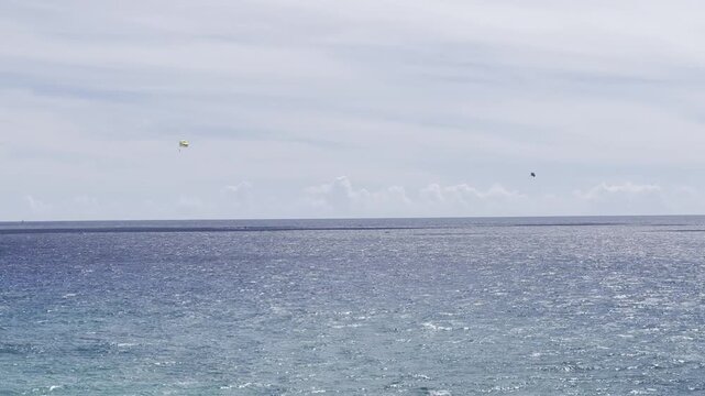 USA, Hawaii, Oahu, Honolulu, Pacific Ocean - Parasailing vacation activity tourists towed behind a boat