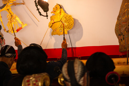 Traditional puppeteer controls colorful wayang kulit figures during a cultural shadow puppet performance at Yogyakarta Palace, Indonesia.