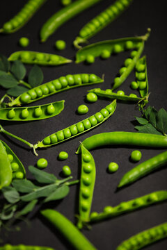 Fresh green pea pods pattern on dark background with selective focus.