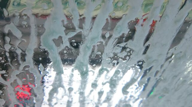 First person view of soap foam spraying on car windshield