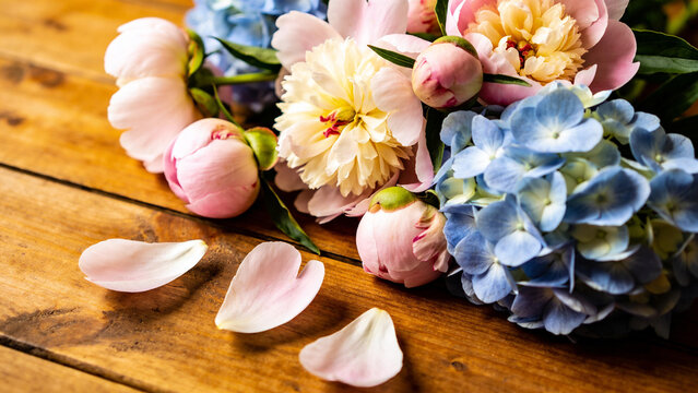 Flowers arranged on wooden surface with petals scattered around in lifestyle setting