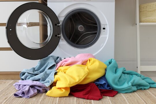 Pile of laundry near washing machine indoors