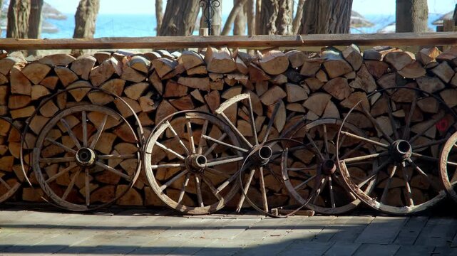 Old Vintage Ladder Wagon Wooden Wheels Leaning Against Stacked Firewood Logs at Countryside Farm Ranch
