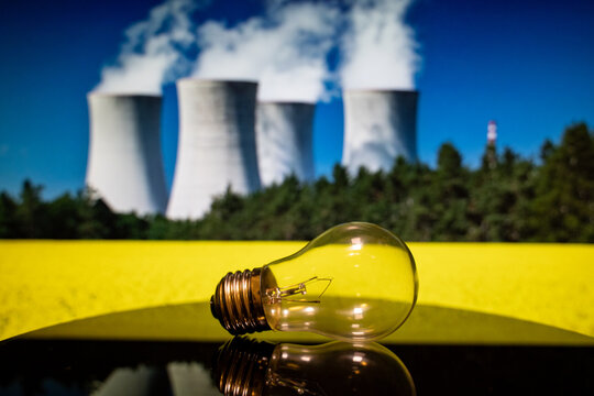 Close up of light bulb with nuclear power plant background.