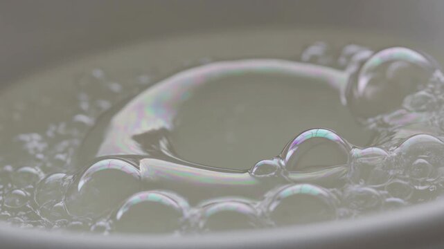 Macro slow motion of soap bubbles swirling with rainbow reflections