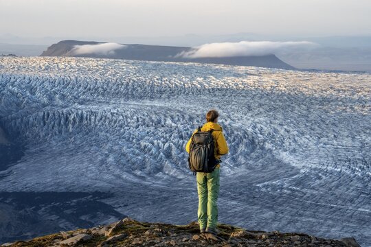 Young man, tourist in front of impressive glacier, in the evening light, glacier tongues K&ouml;tluj&ouml;kull, Myrdalsj&ouml;kull glacier Pakgil, Iceland