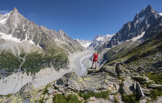 Climber standing on rocks, Grand Balcon Nord, glacier tongue Mer de Glace, behind Grandes Jorasses, Mont Blanc massif, Chamonix, France