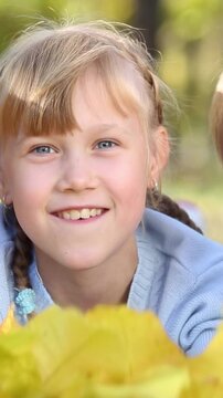 Happy children playing outdoors in the autumn park. Three girl friends having fun outside. Vertical video, slow motion