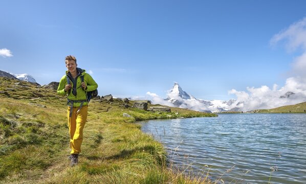 Hiker at Lake Stellisee, 5 lakes Hiking trail, snow-covered Matterhorn at the back, Valais, Switzerland