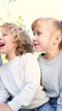 Happy children playing outdoors in the autumn park. Three girl friends having fun outside. Vertical video, slow motion