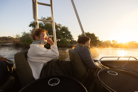  young people experiencing cold sunrise on the Zambezi River, as fog rises from the water, Zimbabwe, Africa