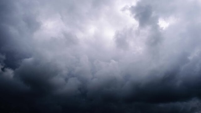 Dark heavy storm clouds churn and gather ominously across the sky covering the last patch of blue. The dramatic movement creates a threatening and foreboding atmosphere.
